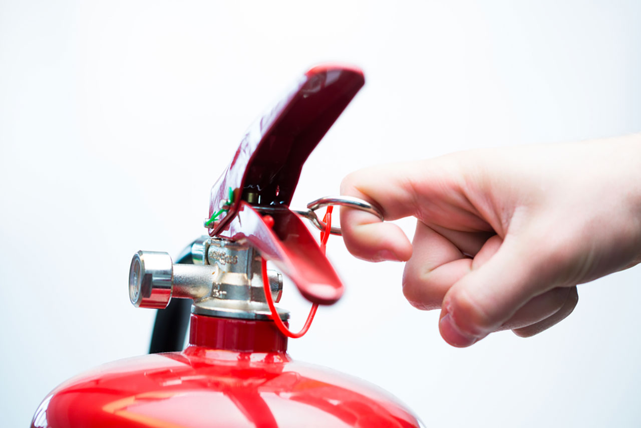 Hand pulling fire extinguisher pin